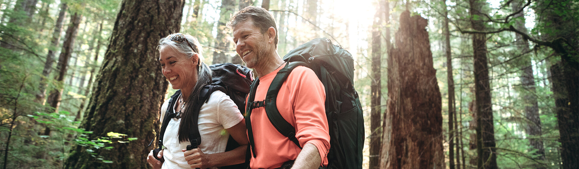 Two adults hike in the woods for cardiovascular exercise