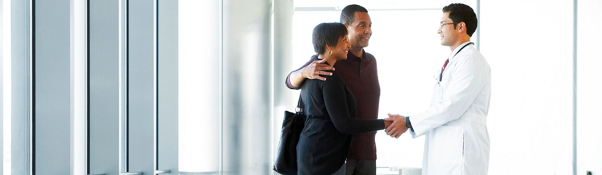 Doctor shaking hands with couple in lobby