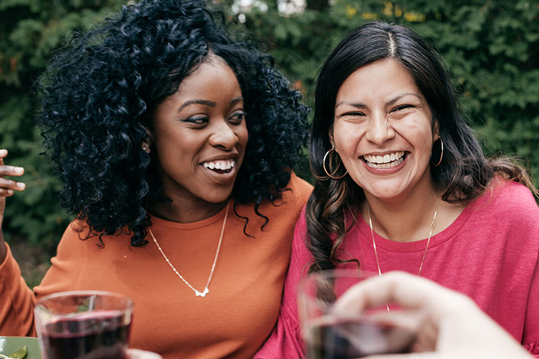 Two women laugh at an outdoor party