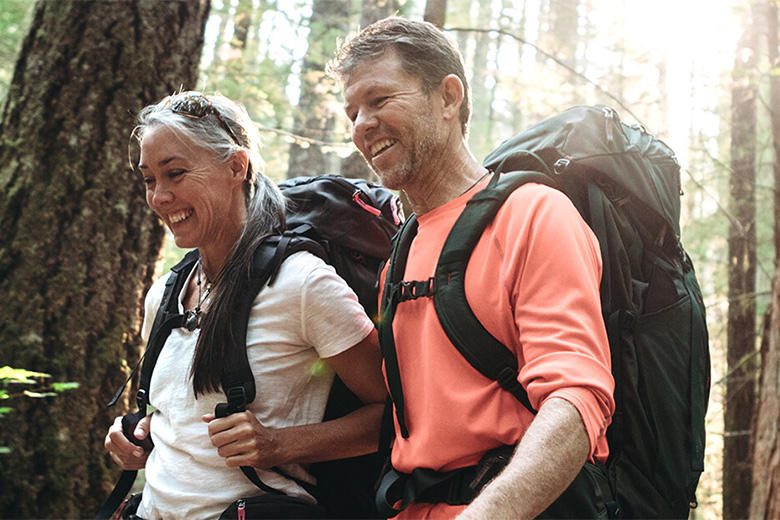 Two adults hike in the woods for cardiovascular exercise