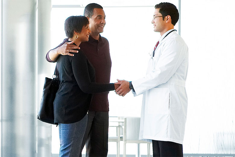 Doctor shaking hands with couple in lobby
